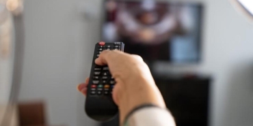 Mature woman holding the TV remote while watching television at home
