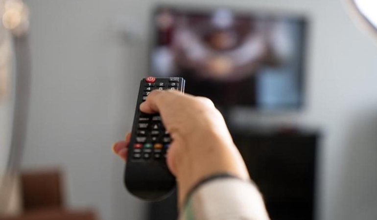Mature woman holding the TV remote while watching television at home